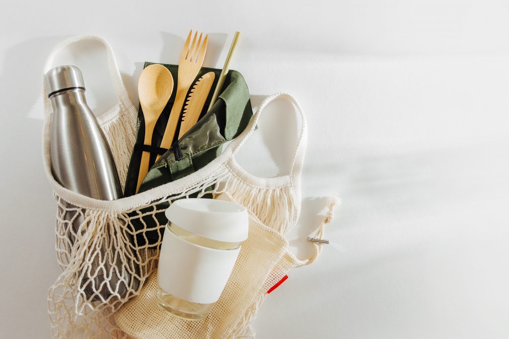 Mesh market bag with bamboo cutlery, reusable coffee mug and water bottle. Sustainable lifestyle. Reduce Plastic Waste concept.