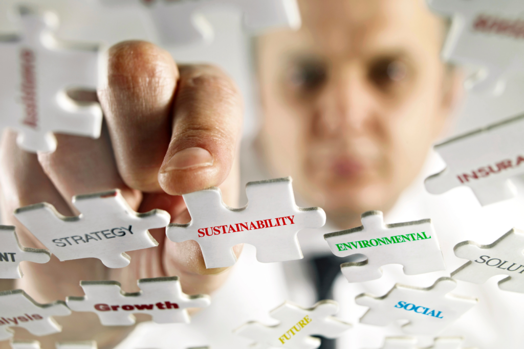Business man putting the pieces of a puzzle together. Puzzle pieces all have key words connected to sustainability